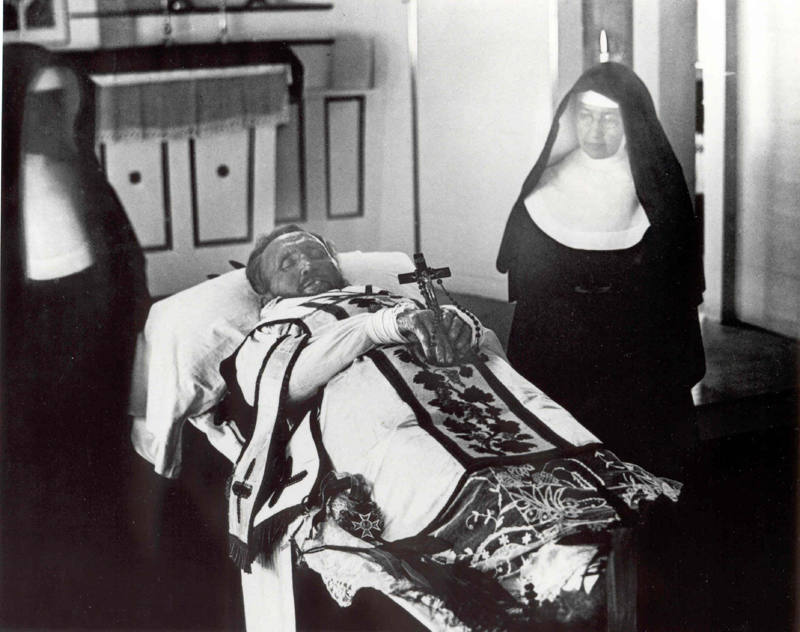 Father_Damien_on_his_funeral_bier_with_Mother_Marianne_Cope_by_his_side_resize