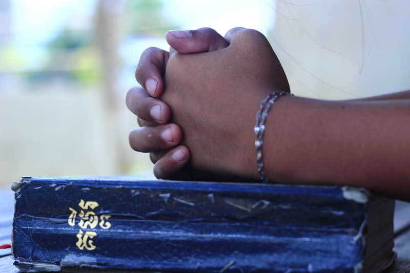 Con le mani sulla Bibbia in lingua khmer. Foto Tep Ro – Pixabay.