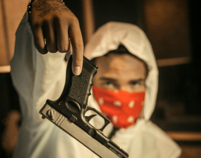 Membro di una banda mostra la pistola. Foto Nathan Costa – Unsplash.