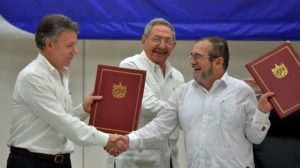 Colombia's President Juan Manuel Santos (L) and Timoleon Jimenez, aka "Timochenko" (R), head of the FARC leftist guerrilla, shake hands accompanied by Cuban President Raul Castro (C) during the signing of the peace agreement in Havana on June 23, 2016. Colombia's govement and the FARC guerrilla force signed a definitive ceasefire Thursday, taking one of the last crucial steps toward ending Latin America's longest civil war. / AFP PHOTO / ADALBERTO ROQUE
