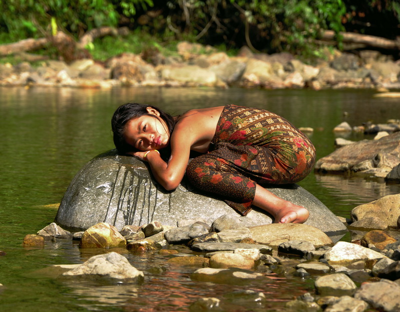 Penan girl, Diana, rests by the river, Malaysia.